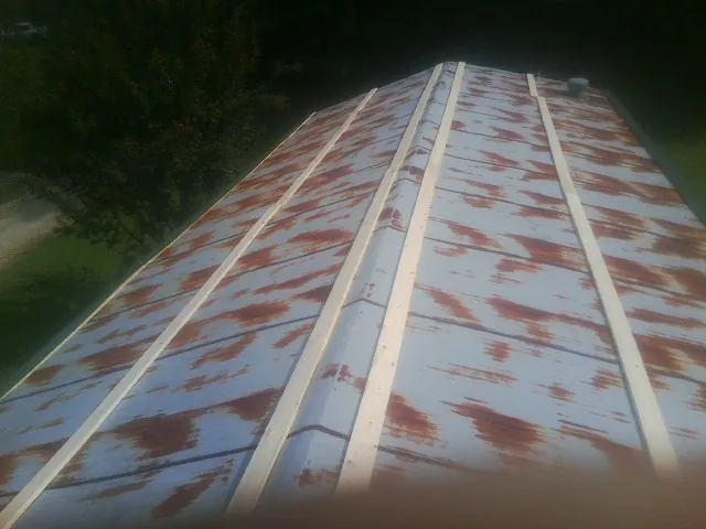 Rusted metal roof panels with new wood purlins before replacement — Storm Damage Roof Repair in La Rose by Roofing Brothers