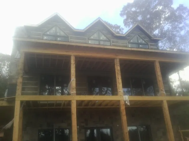 Dormers and porch framing on a large log home under construction — Roof Coating work by our crew in La Rose