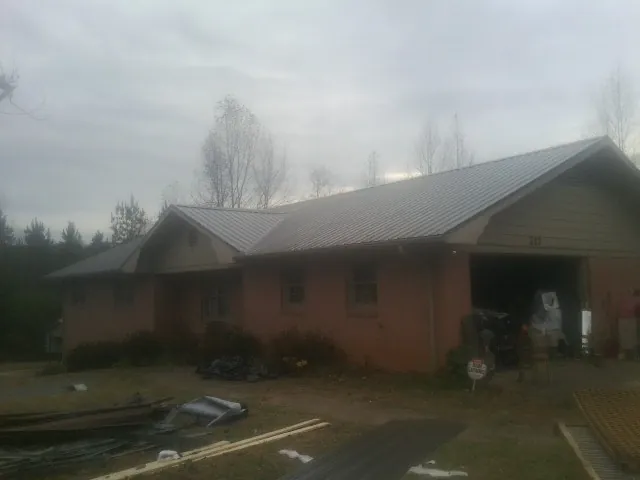 Gray metal roof on a stucco house with an attached garage in La Rose