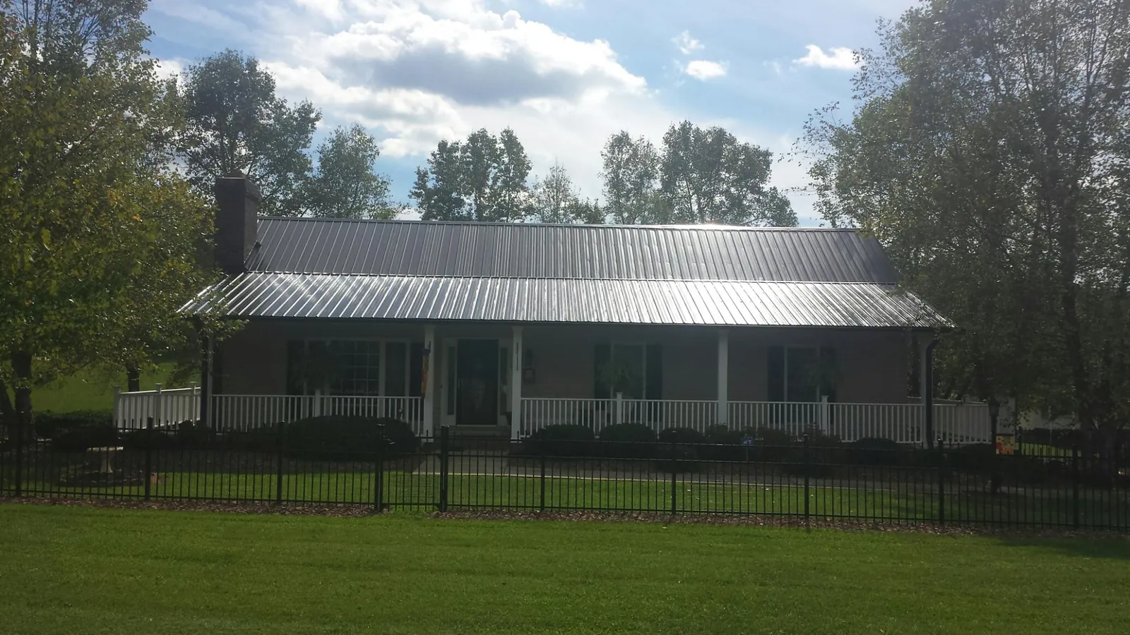 Gray metal roof on a brick ranch with a full width front porch — Gutter Guard Installation work by our crew in La Rose