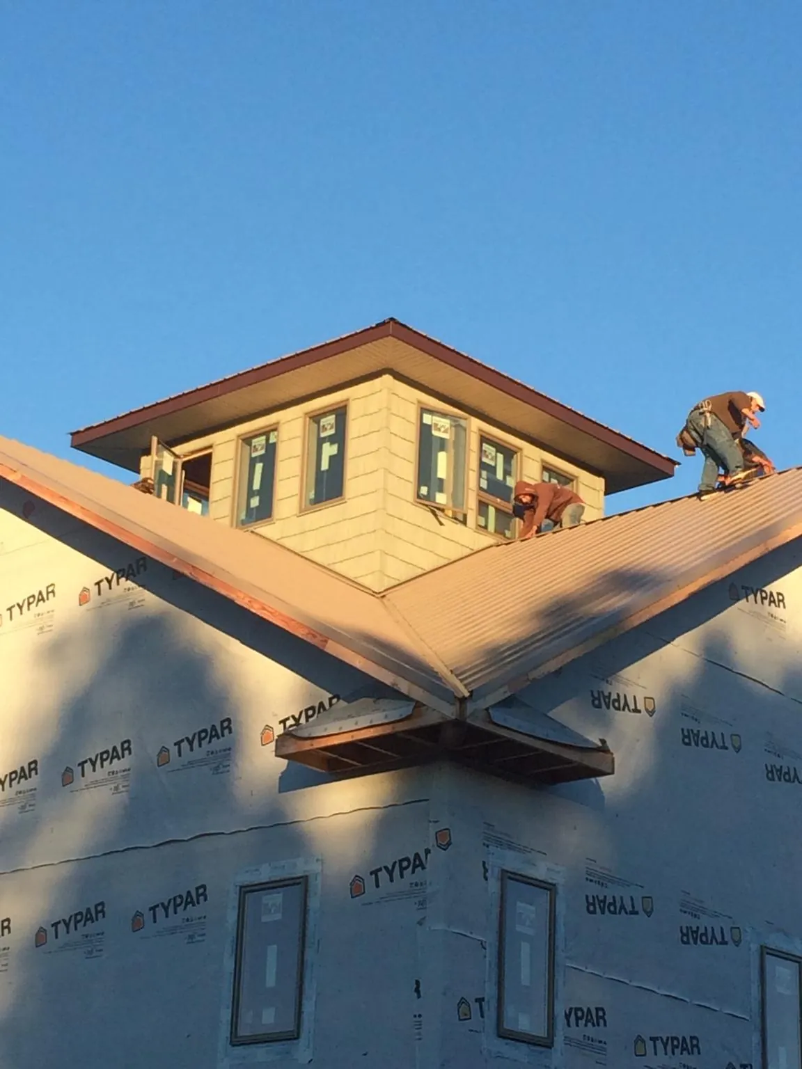 Roofers working around a rooftop cupola on a new metal roof at sunset — Roof Waterproofing in La Rose by Roofing Brothers